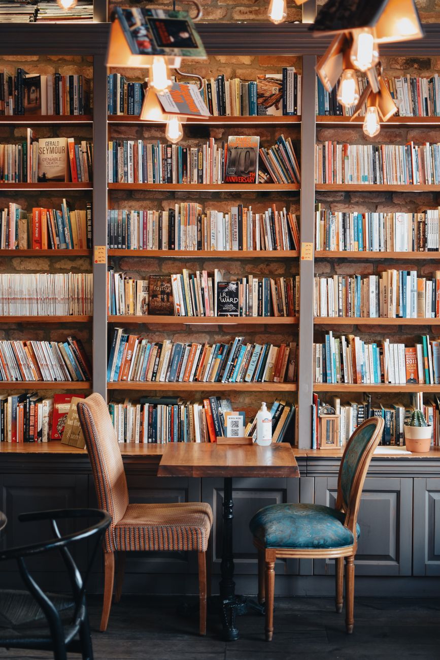 A warm, inviting library corner with wooden bookshelves filled with books and a small table with chairs.