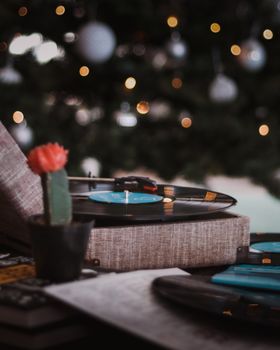 Vinyl record playing on a turntable next to a cactus, set against a Christmas tree bokeh background.