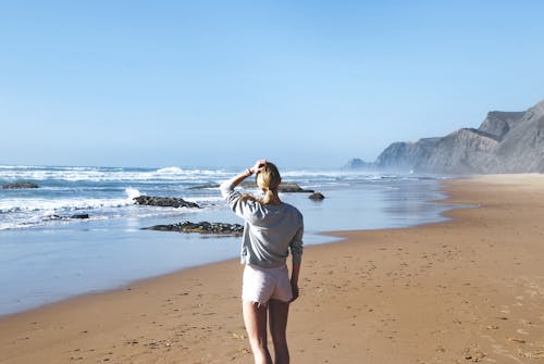 Woman in Gray Long-sleeved Shirt With Pink Short Shorts Standing Near Sea