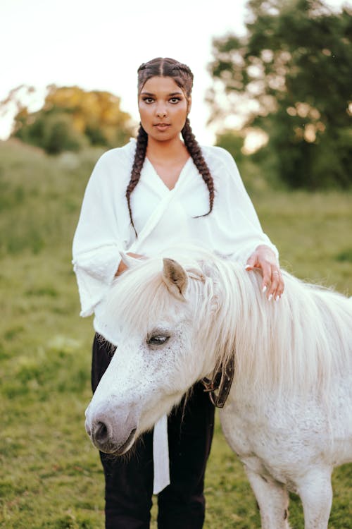 Woman in White Top Standing Beside a Pony