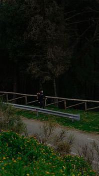 A young adult walks on a rural road lined with lush greenery. Ideal for travel concepts.