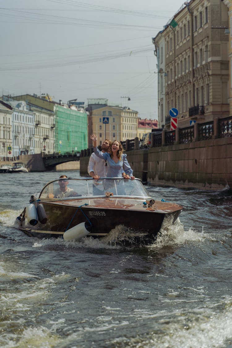 A Couple Having A City Tour Riding A Boat Along The River Canal