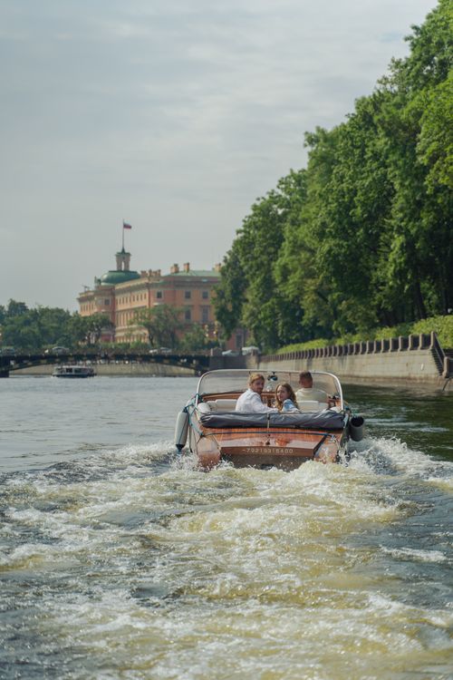 Free Couple enjoys a romantic boat ride along a scenic river with historic architecture in the background. Stock Photo
