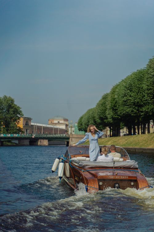 Free A woman enjoys a scenic boat ride under a clear blue sky, surrounded by lush trees and calm water. Stock Photo
