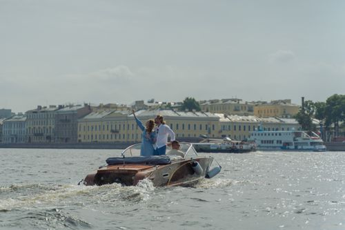 Free A couple enjoys a romantic boat cruise on a sunny day alongside historic urban architecture. Stock Photo