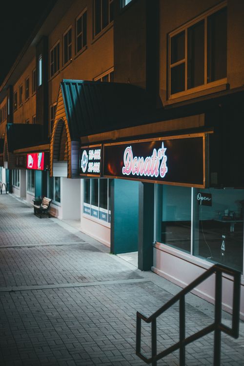 Free Street view showcasing illuminated storefronts and handrails at night. Stock Photo