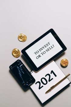 Flat lay of bitcoins, gadgets, and a 2021 calendar exploring investment choices.