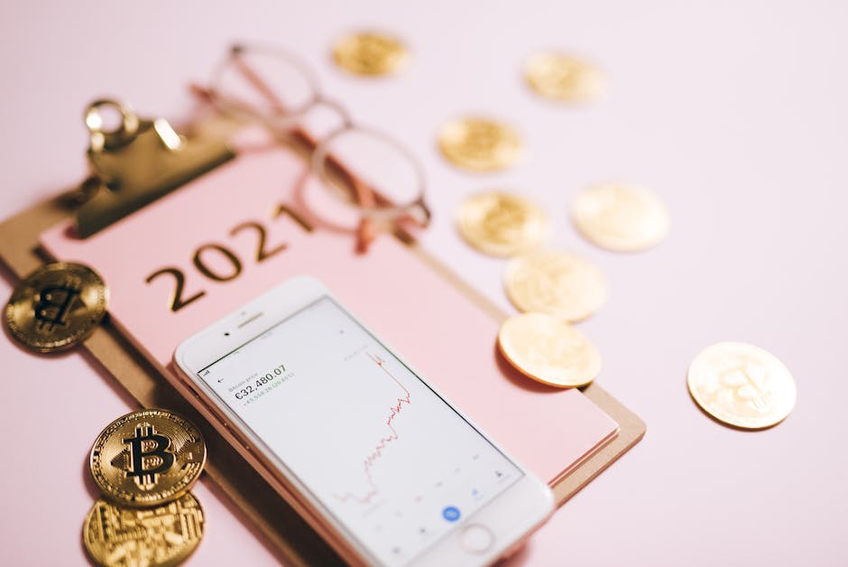 Close-up of a smartphone with crypto chart, bitcoin coins, and 2021 notepad.