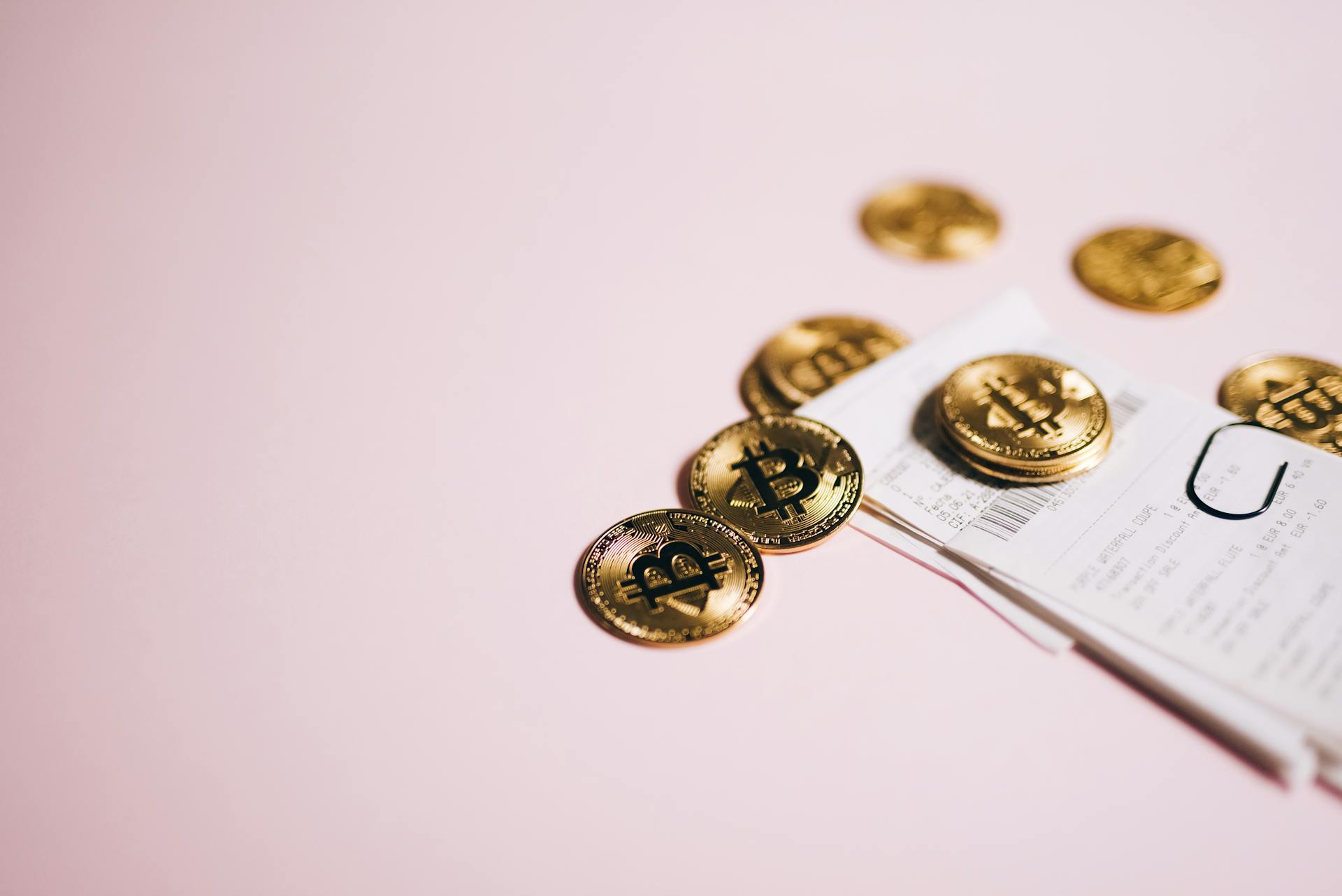 Bitcoins and a Receipt on Pink Background