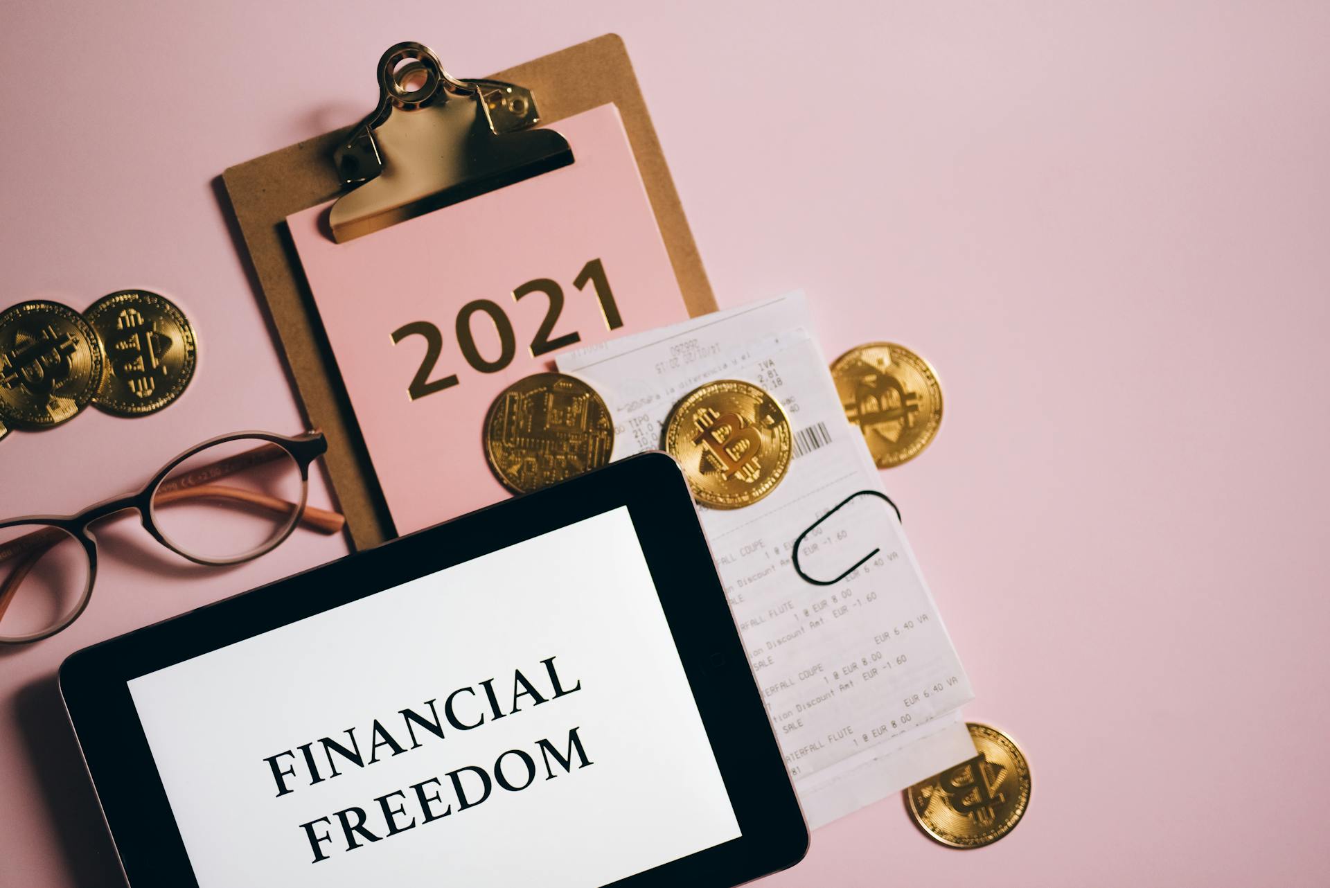 Stylish flat lay of financial elements including cryptocurrency and tablet displaying 'Financial Freedom'.