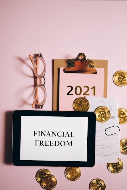 A Tablet and Gold Coins on a Pink Surface