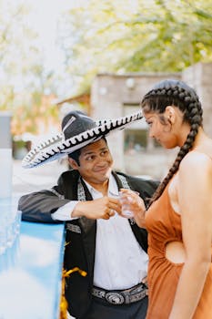 Couple enjoying a romantic interaction outdoors in traditional Mexican attire.