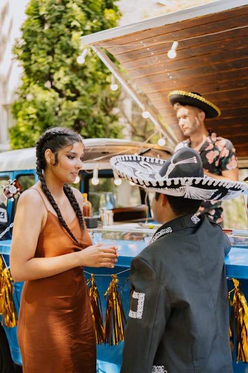 Brunette Woman in Orange Dress and Musician in Sombrero