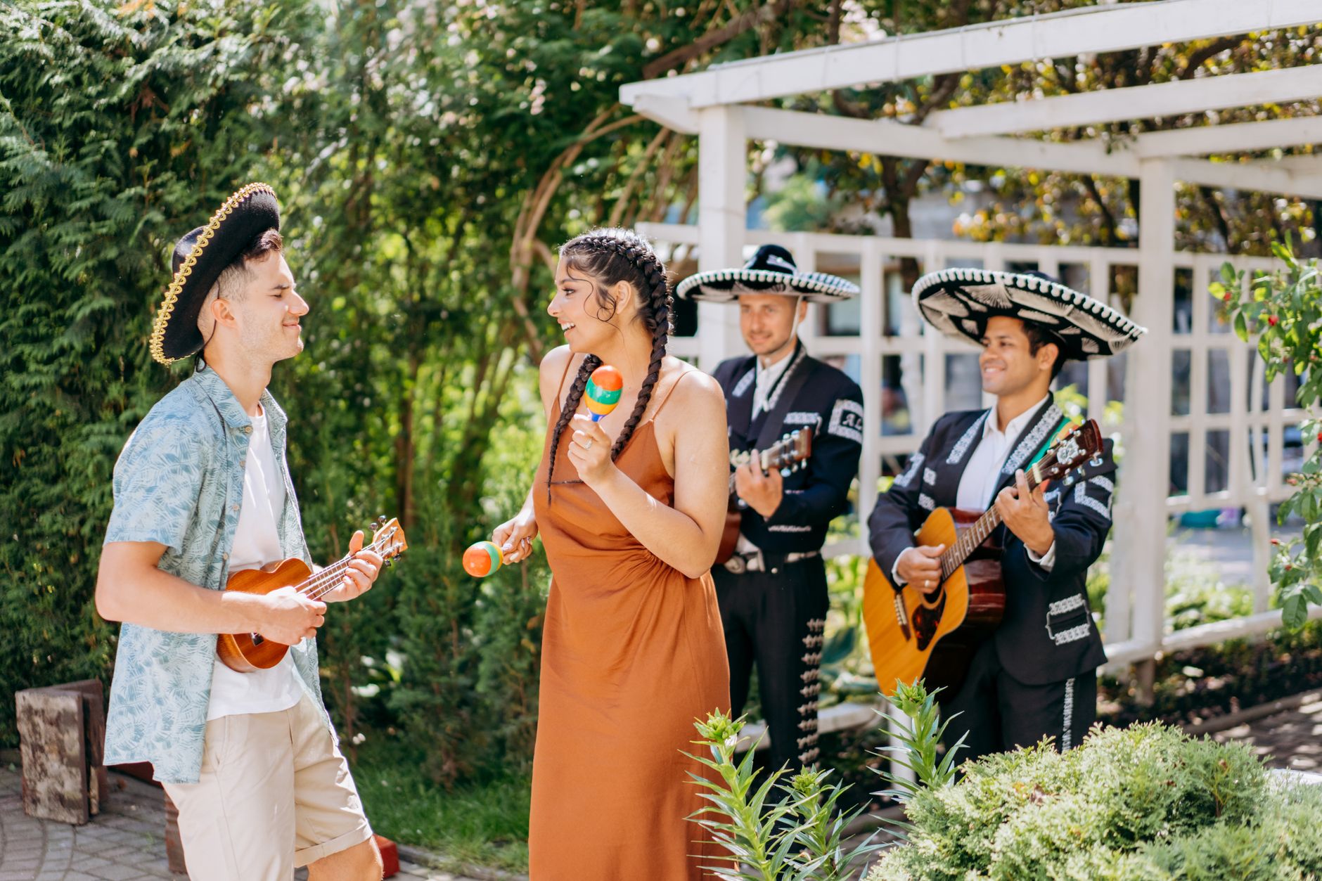 Group enjoying traditional Mexican music outdoors with sombreros and instruments.