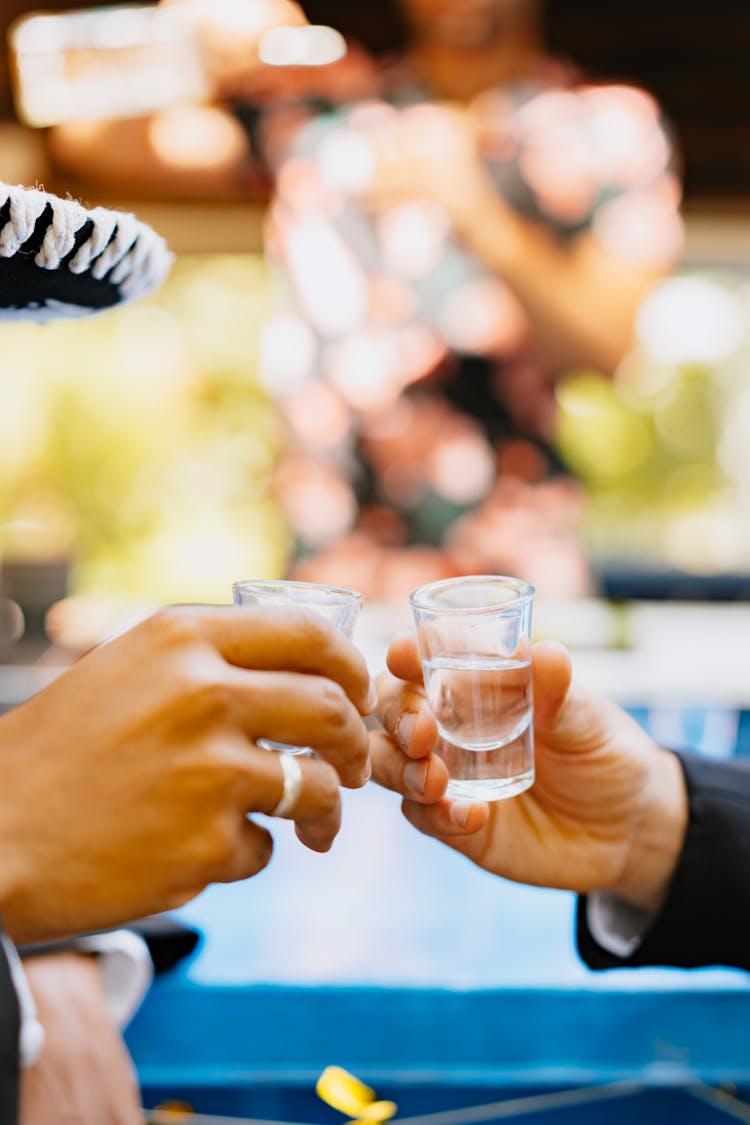 Hands Holding Shot Glasses 