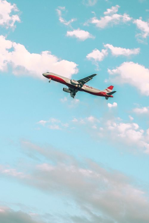 Free A passenger airplane flying through a bright blue sky with fluffy clouds, viewed from below. Stock Photo