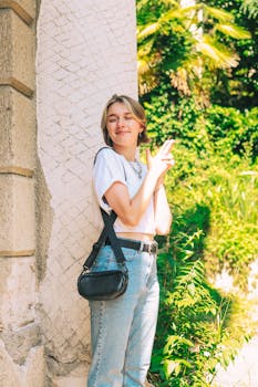 Woman smiling and enjoying a sunny day outdoors with greenery around.
