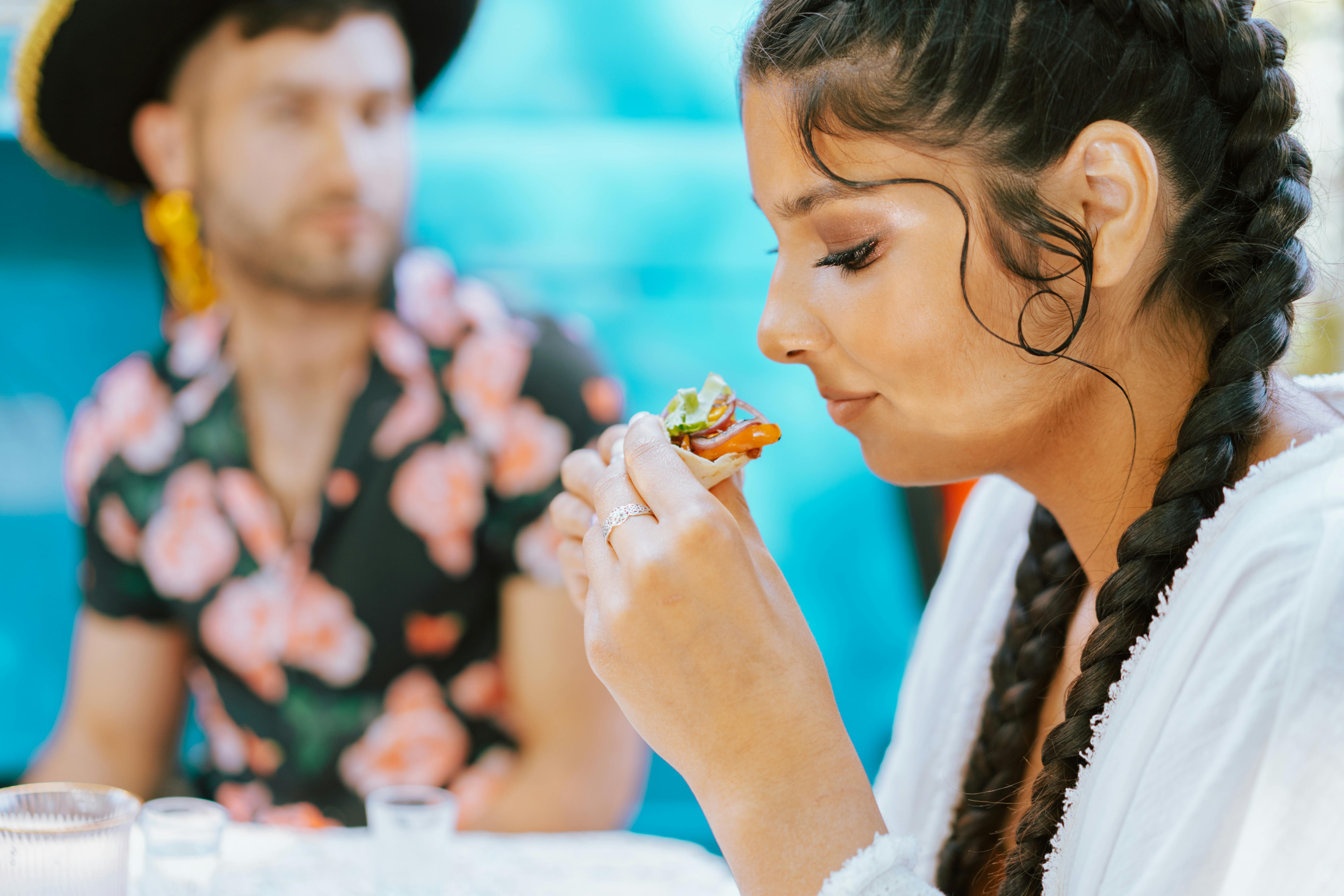 Free Young woman savoring a delicious snack at an outdoor gathering during summer. Stock Photo