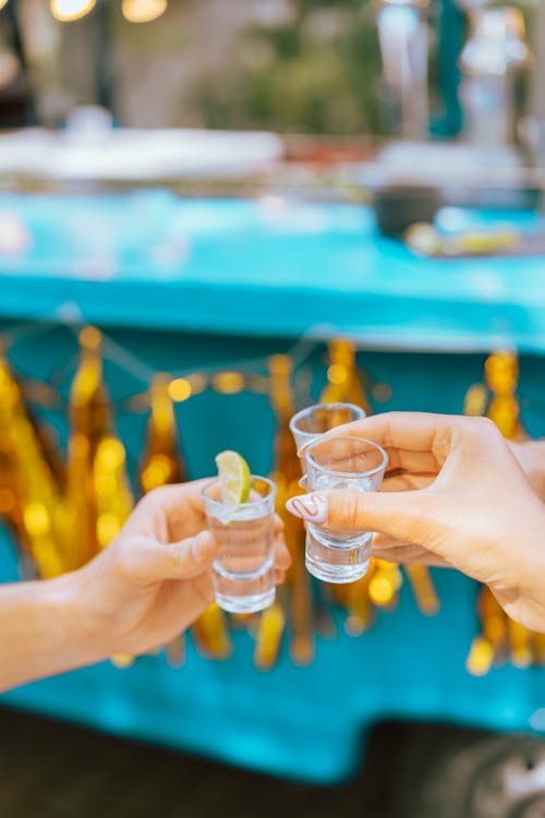 Close-Up Shot of People Holding Glasses of Tequila