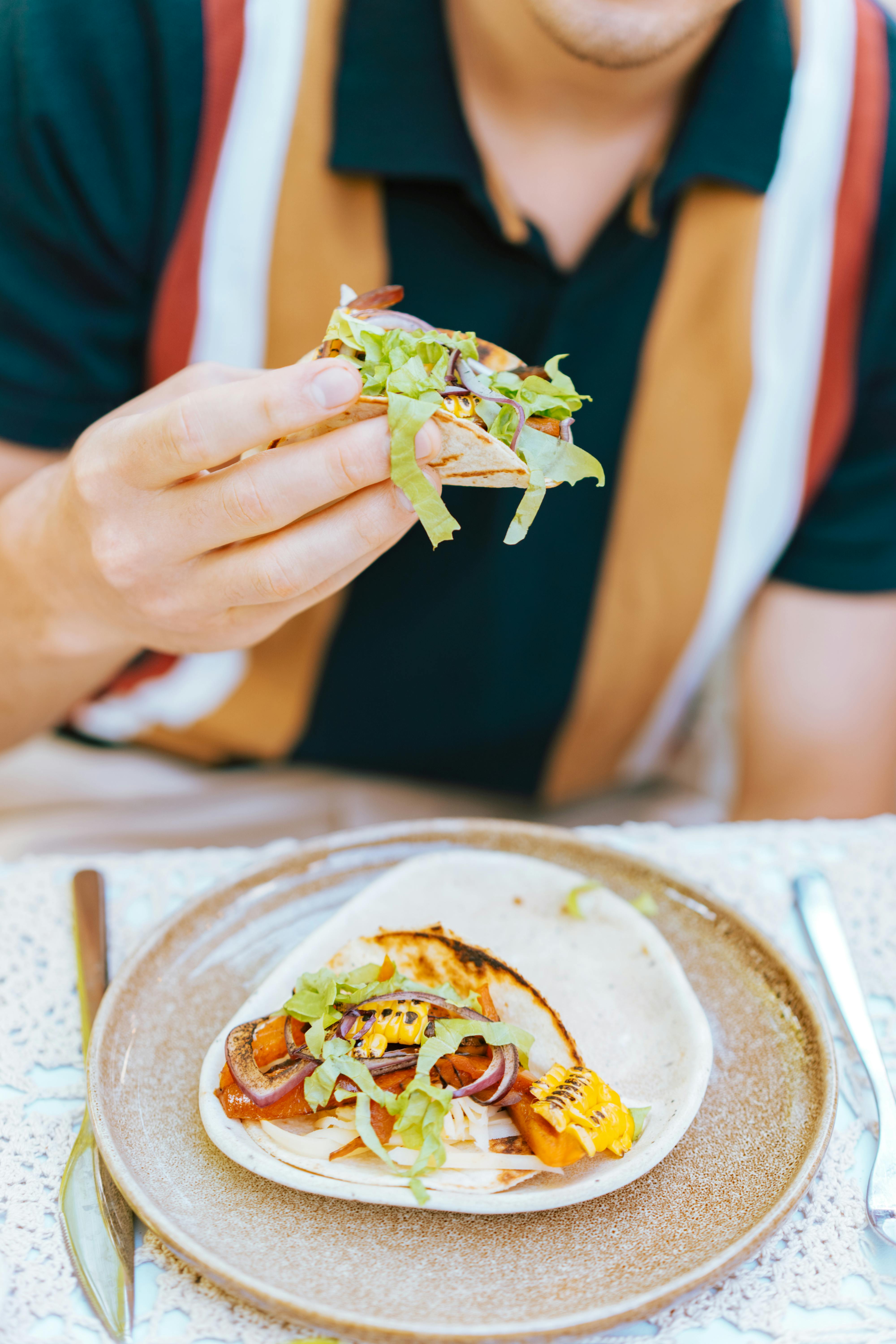 Free A person savoring a delicious taco filled with grilled vegetables and lettuce. Stock Photo