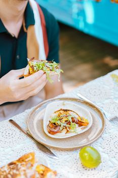 Close-up of a person eating tacos with fresh ingredients at an outdoor picnic setting.