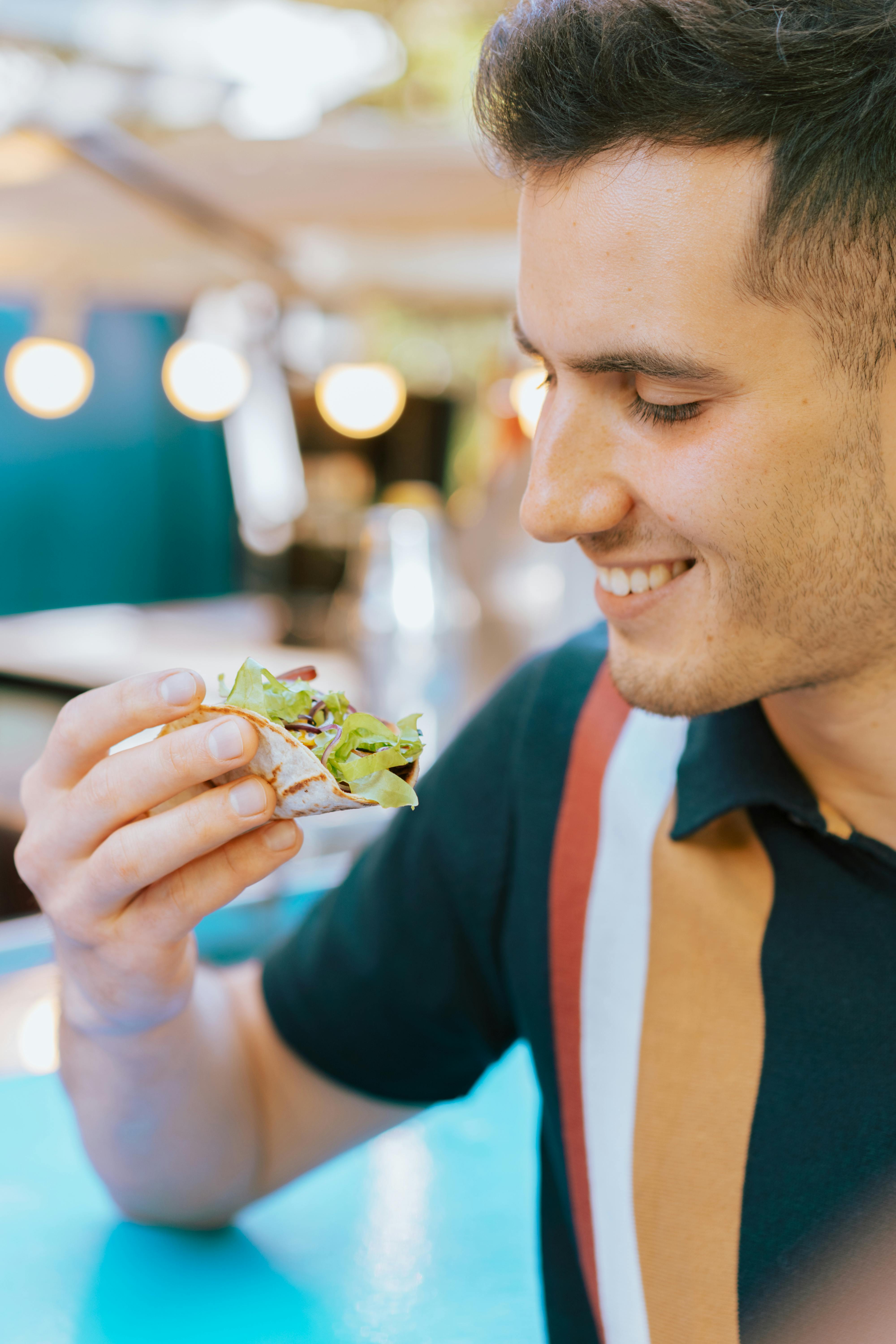Free A smiling man enjoys a delicious plate of fresh nachos at an indoor setting. Stock Photo