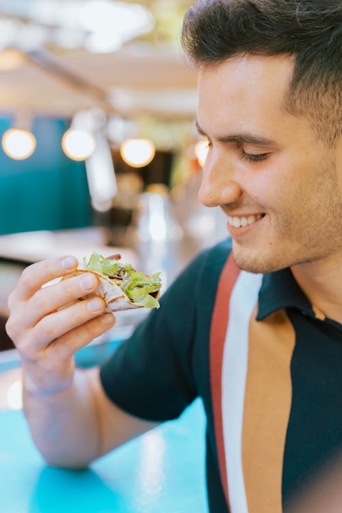 Free A smiling man enjoys a delicious plate of fresh nachos at an indoor setting. Stock Photo