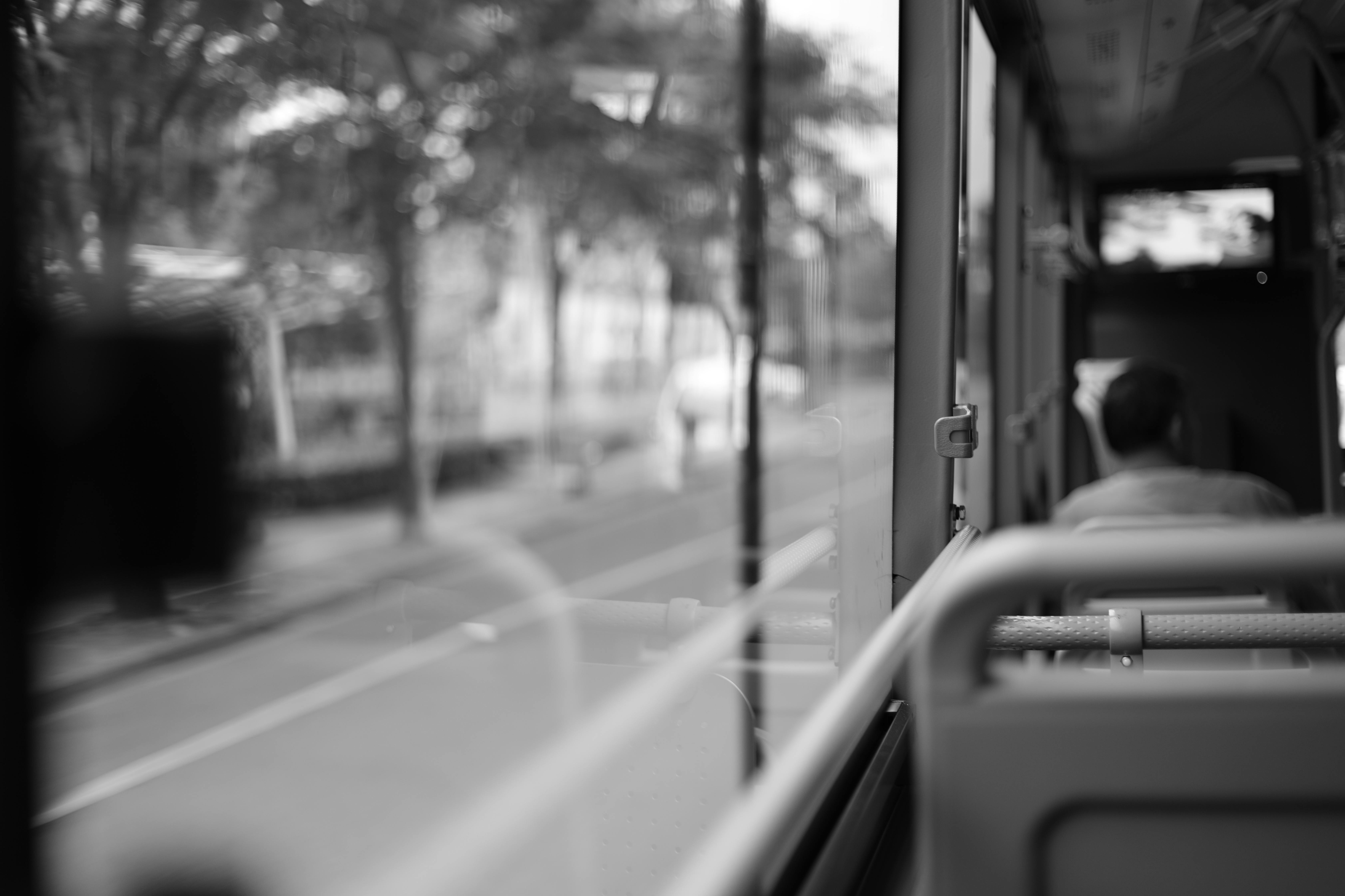 grayscale photo of a point of view of a person sitting inside a bus