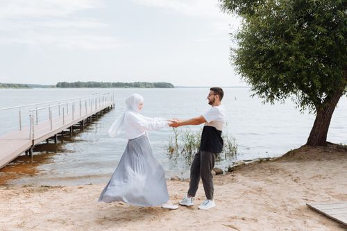 Free A happy couple dances by the waterside with a dock nearby. Stock Photo