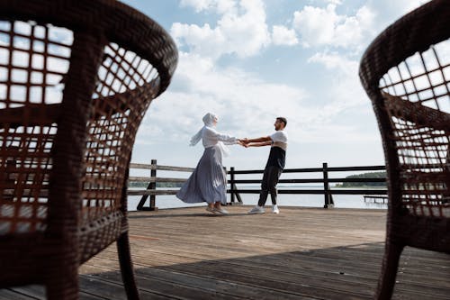 A Romantic Couple Holding Hands on a Wooden Dock