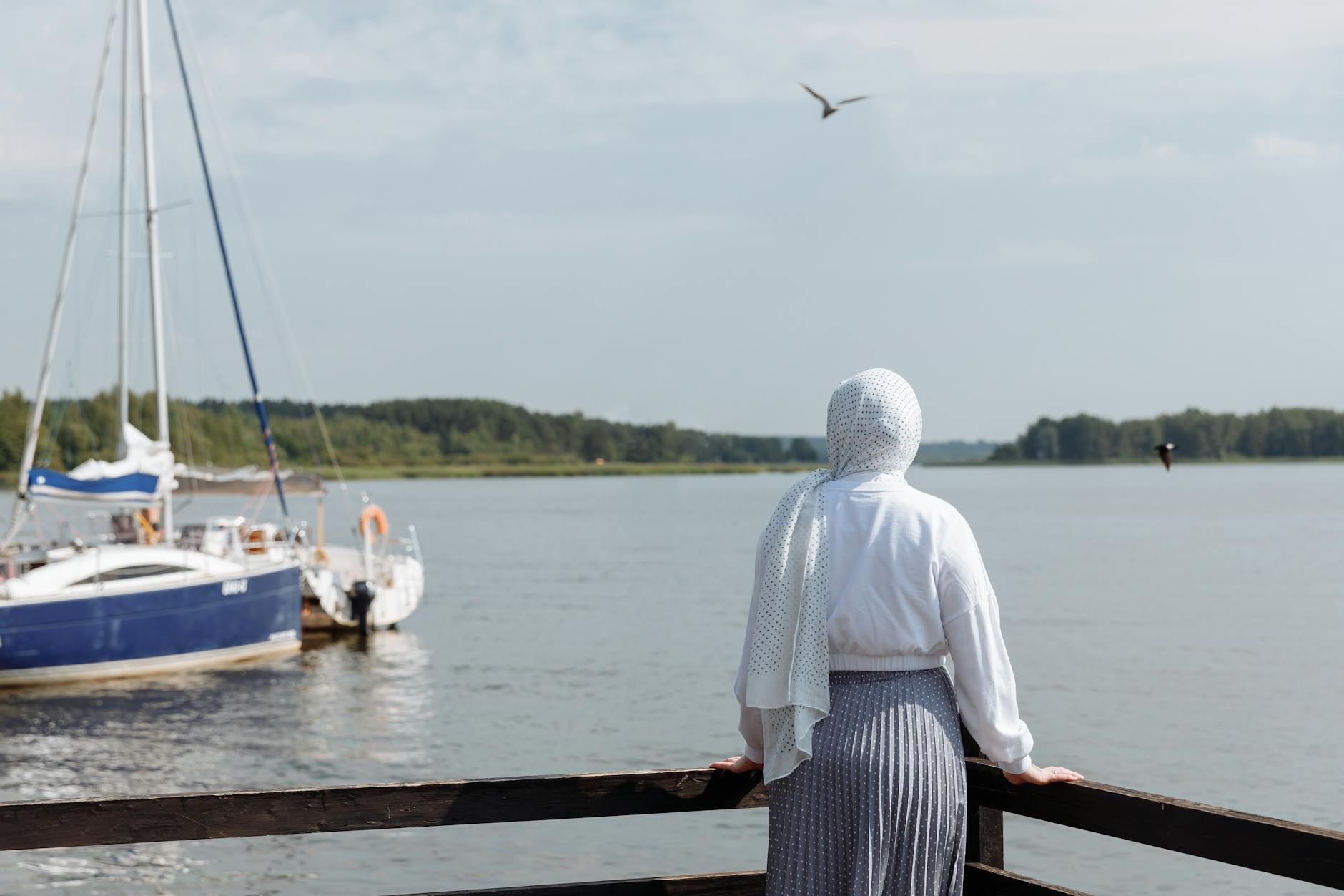 A Woman in White Hijab Standing Beside the Wooden Fence