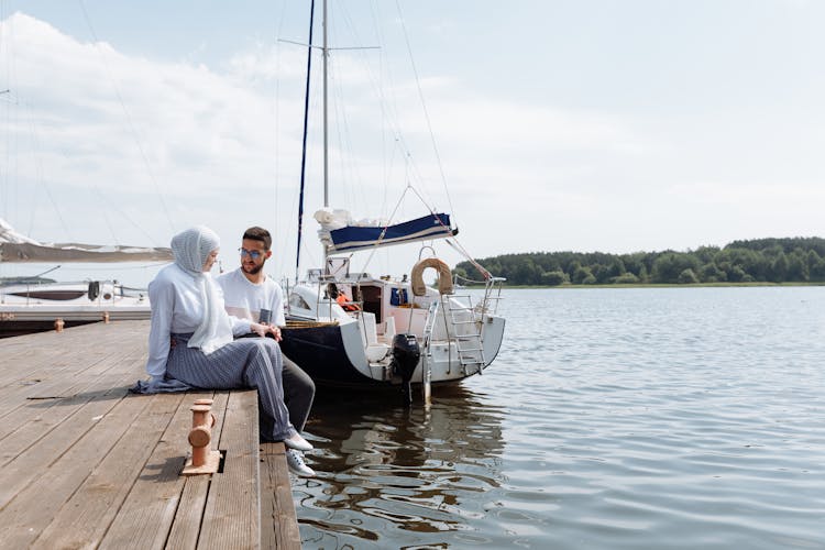 A Couple Sitting On Wooden Dock