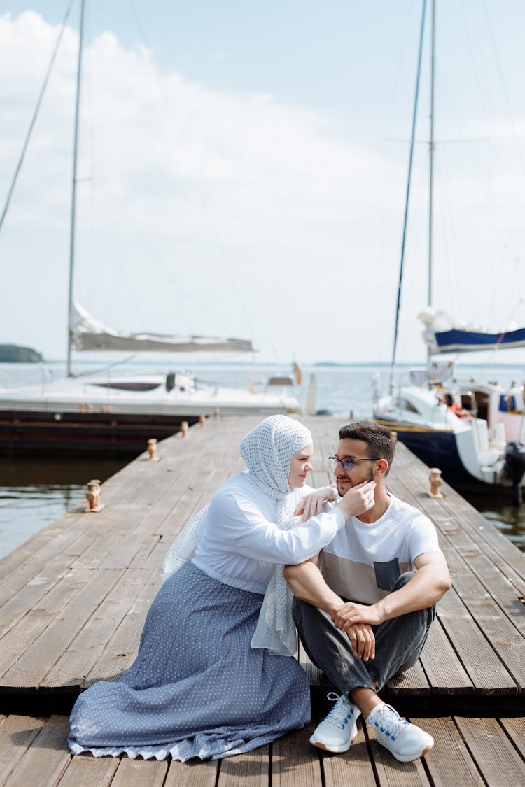 A Romantic Couple Sitting On A Wooden Dock