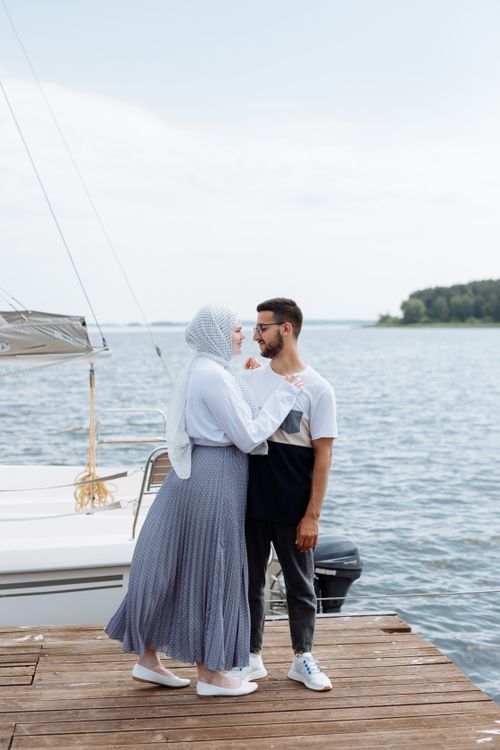Free A loving couple embrace on a wooden dock near the ocean, sharing a tender moment. Stock Photo