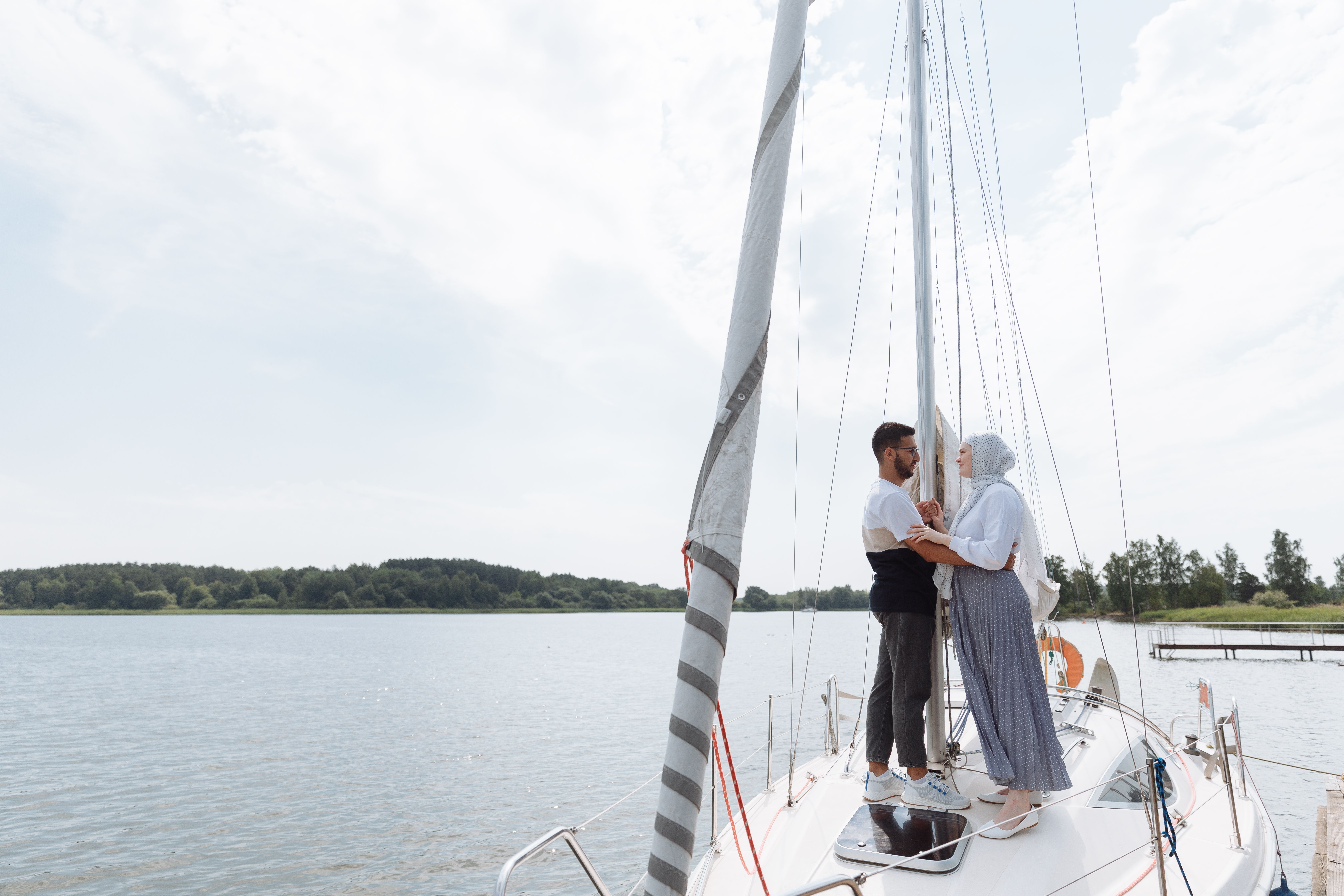 Muslim couple embracing on a sailboat, expressing love and tranquility on a sunny day.