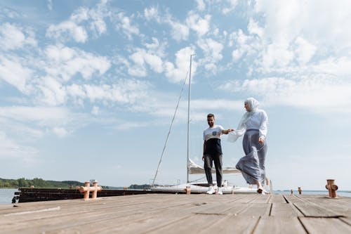 Man and Woman Standing on Brown Wooden Dock