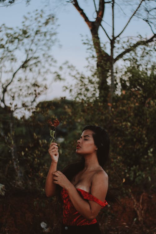 Woman Closing Her Eyes While Holding Red Flower