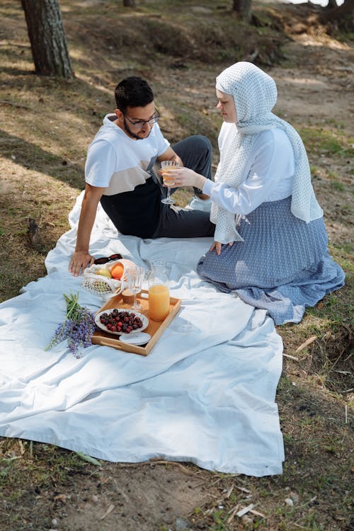 Free A Woman Wearing Hijab Serving a Glass of Beverage to a Man Stock Photo