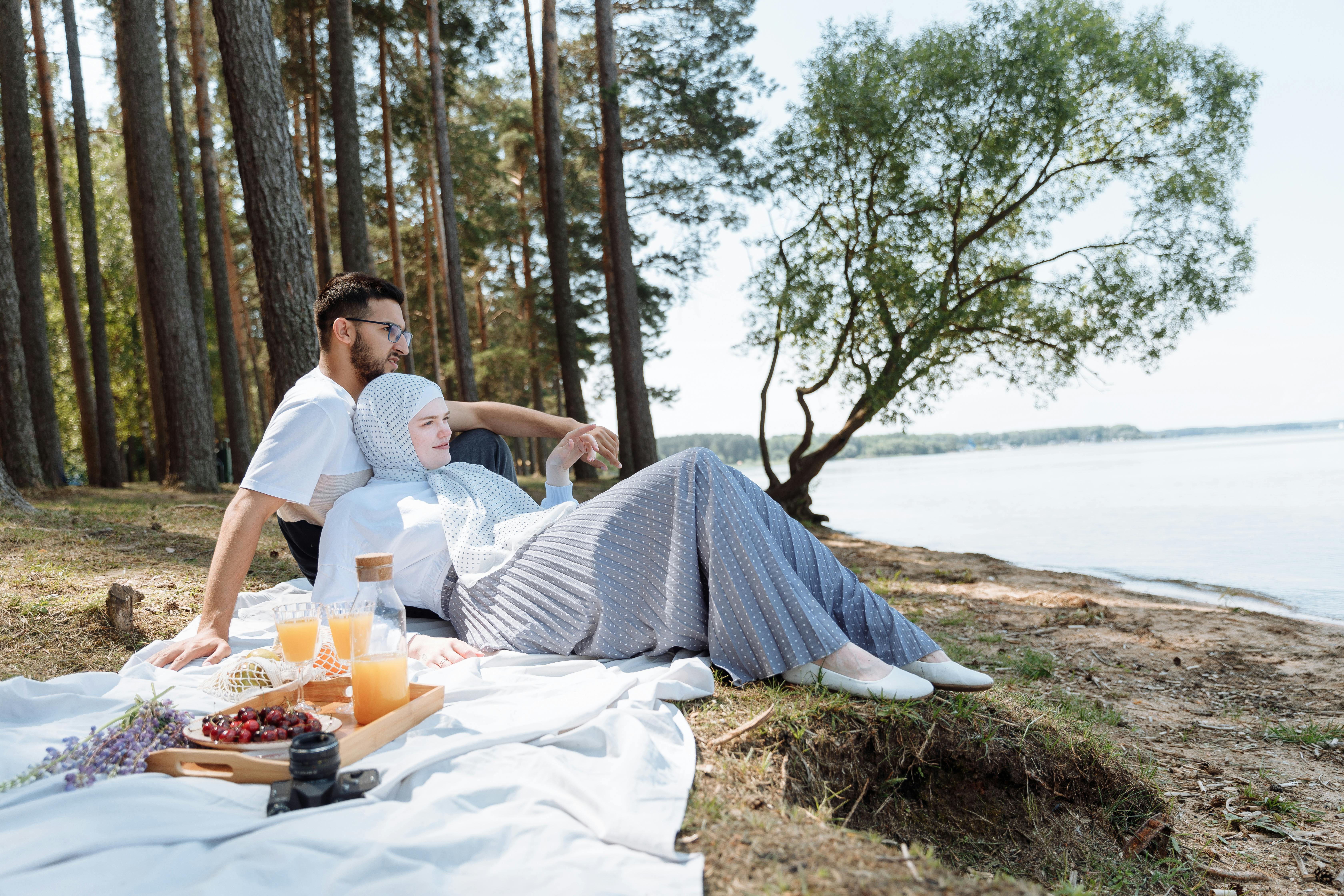A serene picnic by the lake with a couple enjoying drinks and nature.