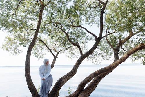 A Woman in White Hijab Sitting on a Tree Branch