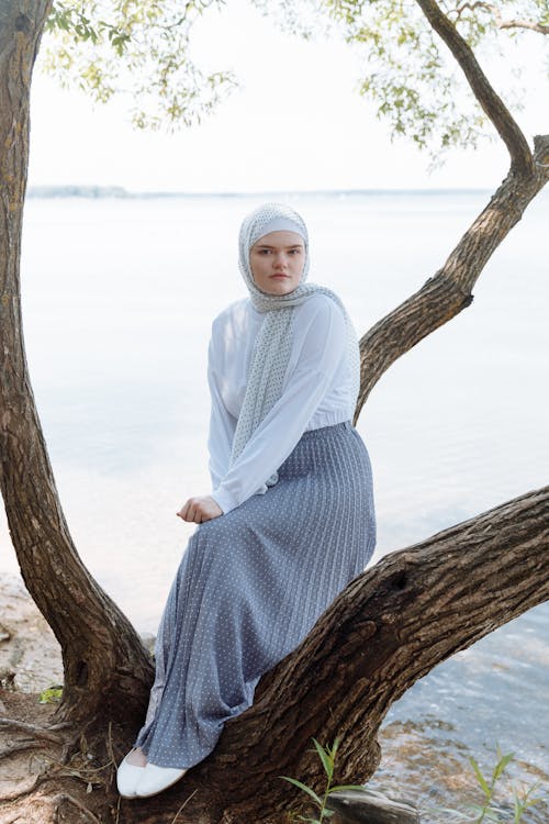 A Woman Wearing Hijab Sitting on a Tree Trunk