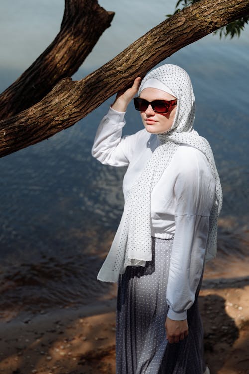 Photo of a Woman with Brown Sunglasses Touching a Tree