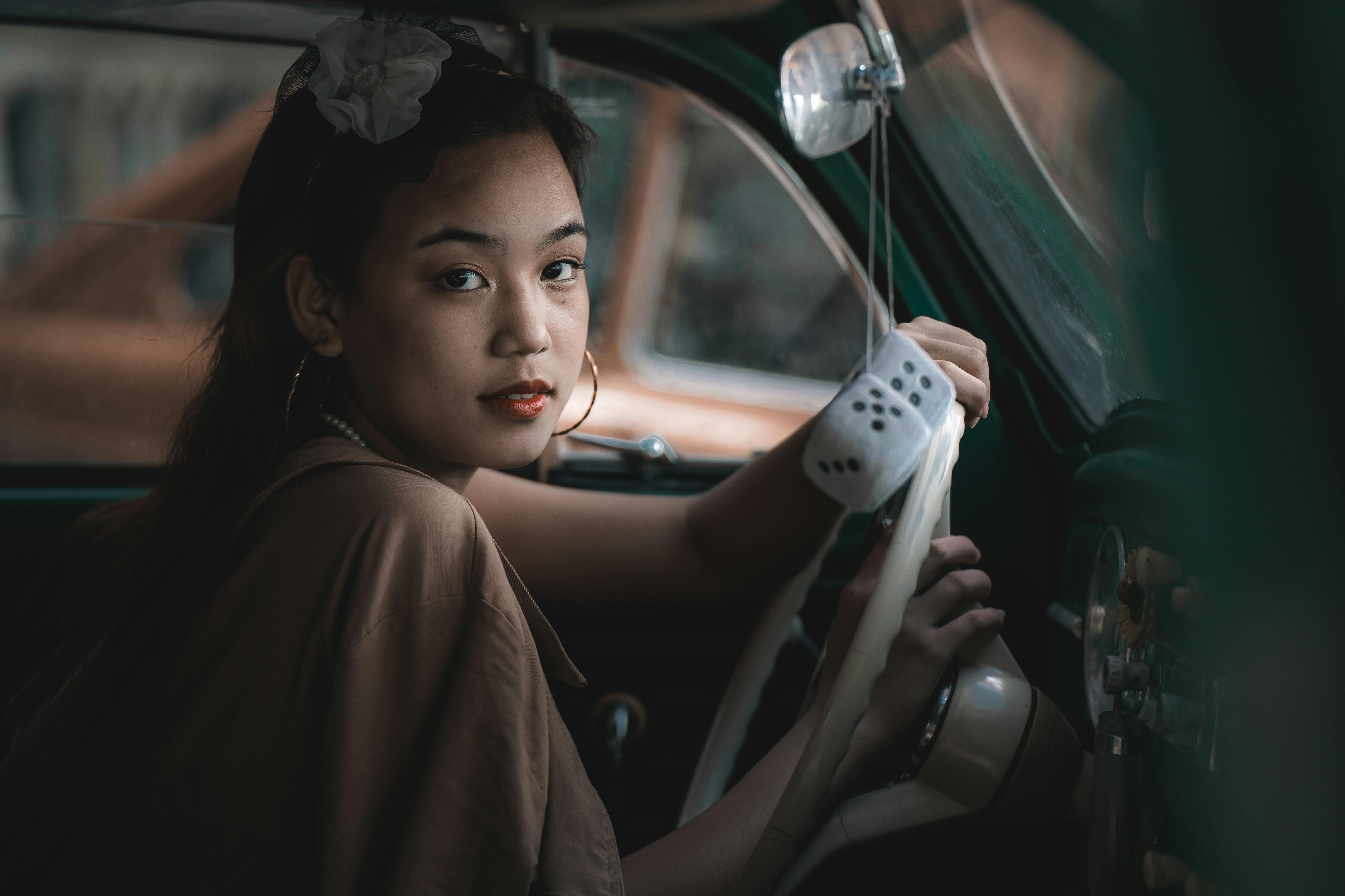 Young woman driving a classic car, adding a vintage charm and elegance.