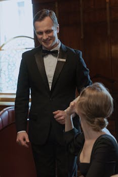 A waiter in a tuxedo serves a woman during a refined dining experience in an elegant restaurant.