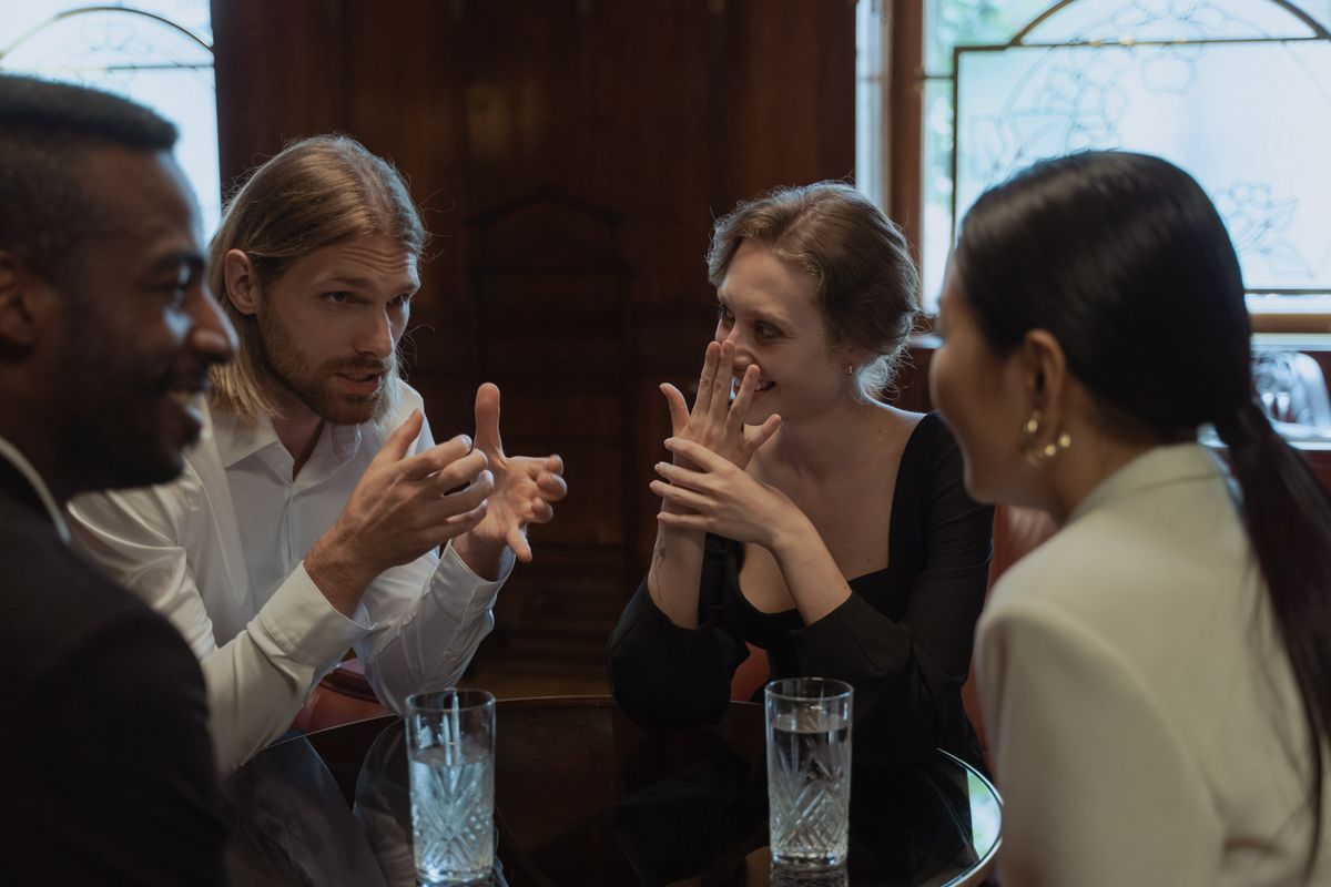 Groupe d’amis discutant autour d’une table dans un intérieur chaleureux