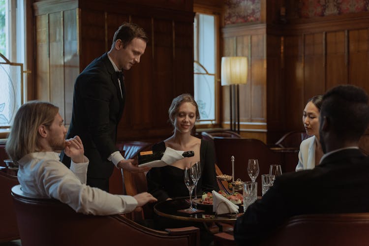 Photo Of A Waiter Pouring Wine Into Glasses