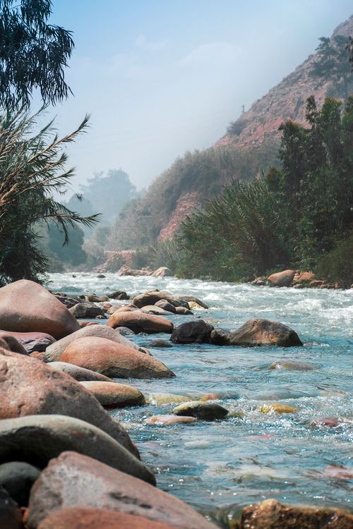 Free Tranquil river with rocky banks and lush vegetation in Chosica, Peru, captured on a clear day. Stock Photo