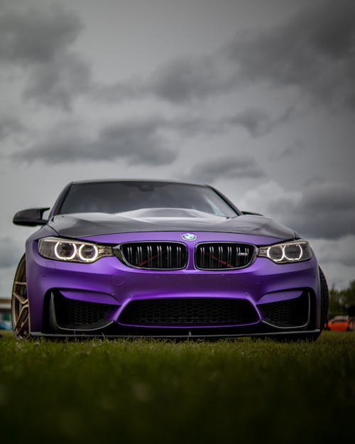 A Purple Bmw  On Grass Under Dark Clouds