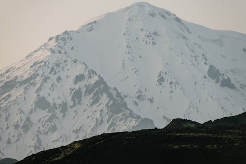 A Snow Covered Huge Mountain Beside a Black Mountain