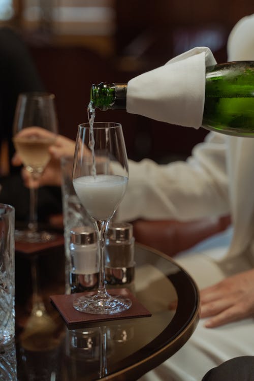 Person Pouring White Wine into a Glass